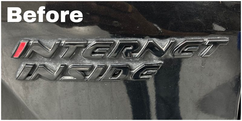 Before black plastic restoration — hazy, oxidised black badge trim